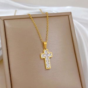 Macro detail of gold cross pendant featuring square zircon stones and fine O-link chain