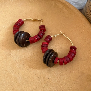 Détail de boucles d'oreilles rondes bohèmes avec perles de bois rouges et marron