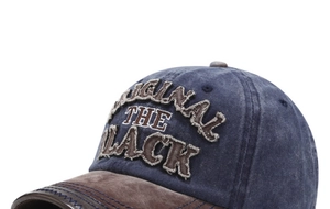 Detailed close-up of vintage washed denim baseball cap with brown brim and embroidery