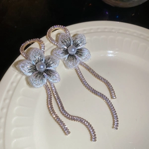 Vue macro de boucles d'oreilles fleurs argentées avec perles et strass sur céramique