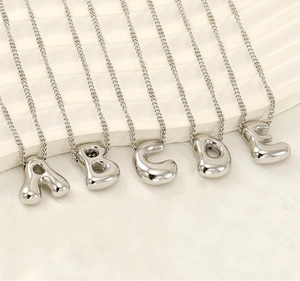 Polished silver bubble initial necklaces from letters A to E on white background
