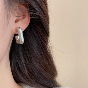 Close-up of minimalist matte silver J-shaped geometric earrings worn by a model