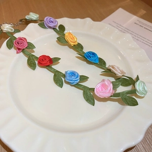 Detailed top view of a colorful rose flower garland necklace on a white scalloped plate