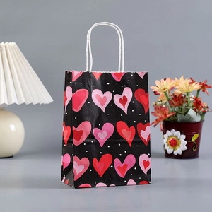 Elegant black kraft paper gift bag with red heart patterns and white rope handles