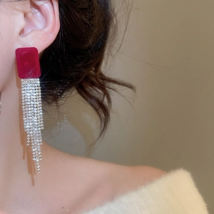 Dettaglio degli orecchini in velluto rosso con lunghe nappe di strass scintillanti