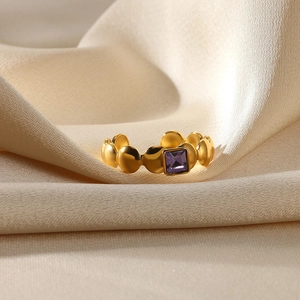 Detailed macro view of gold bubble ring featuring a square purple gemstone on silk