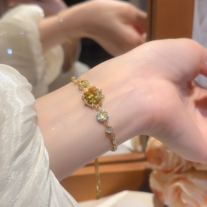 Close-up of 18k gold plated bracelet with yellow oval zircon stone on female wrist