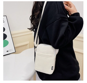 Close-up of white fabric crossbody bag with adjustable strap and Sport tag on model