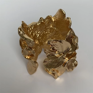 Detailed view of the gold embossed leaf pattern and texture on the wide open cuff bracelet