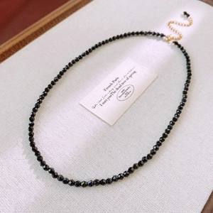 Close-up of faceted black beads with gold lobster clasp on minimalist vintage necklace