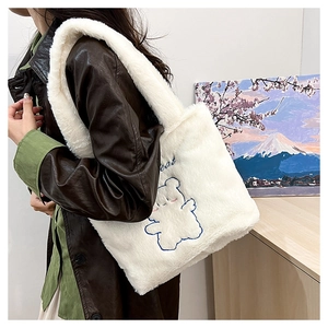 Détail d'un sac fourre-tout en peluche crème avec broderie de petit ours mignon