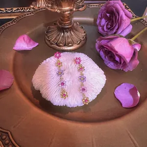 Boucles d'oreilles fleuries avec pierres roses et violettes sur fond de coquillage