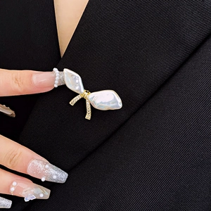 Detailed view of baroque pearl bow brooch pinned on a black textured blazer
