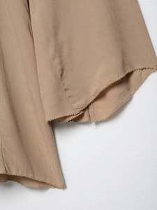 Close-up of beige chiffon dress showing high-quality texture and wavy overlock edge detail