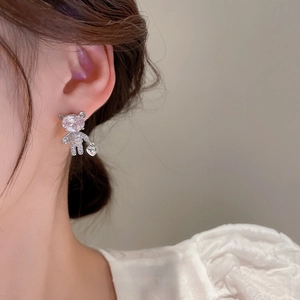 Asymmetric bear heart zircon stud earrings in silver on model's ear for feminine look