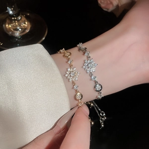 Close-up of gold and silver snowflake bracelets with cubic zirconia on a female wrist