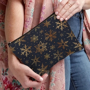 Navy blue cosmetic bag with golden snowflake patterns held by a model for daily use
