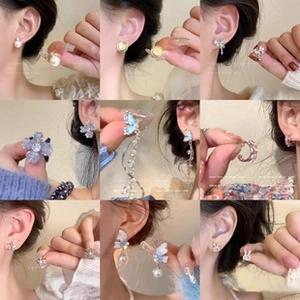 Collage of pearl studs, butterfly tassel earrings and crystal hoops in gold and silver