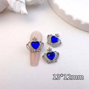 Macro shot of silver crown heart nail art charm with deep blue crystal on nude nails