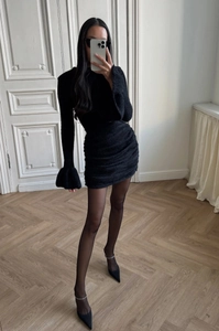 Détail de robe courte noire ajustée avec manches évasées et texture en maille froncée