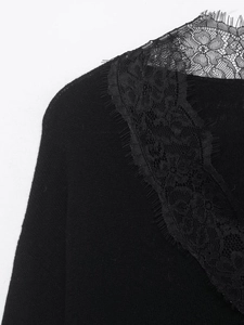 Close-up of black knit top featuring elegant eyelash lace trim on a deep V-neckline