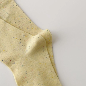 Detailed close-up of yellow knit crew socks with colorful dots and soft fabric texture