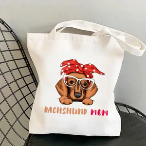 Detailed close-up of white canvas tote bag featuring cute cartoon dachshund mom print