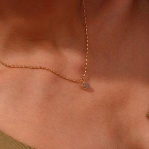 Macro shot of gold bead chain necklace with translucent round natural stone on model