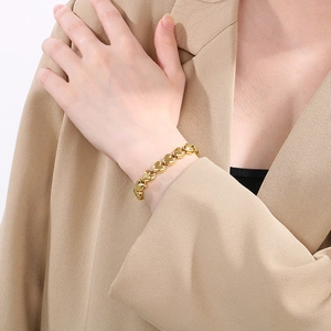 Golden 3D heart link bracelet in stainless steel worn by a model in a luxury suit