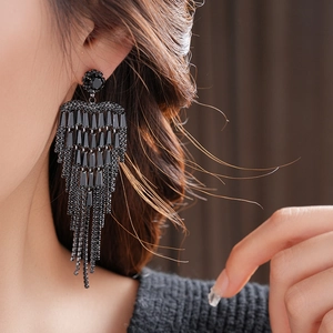 Detailed view of long black tassel earrings with layered trapezoid rhinestones on model