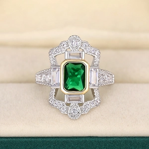 Vista macro de anillo con piedra verde talla esmeralda y detalles de circonitas