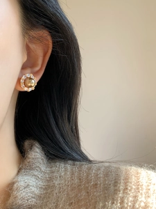 Side view of champagne pearl stud earring with pavé zircon halo on a model's ear