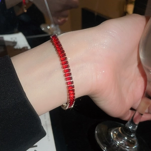 Detail of red rectangular zircon bracelet with gold-plated setting on model wrist
