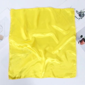 Detailed view of yellow satin square scarf showing silk texture and stitched edges