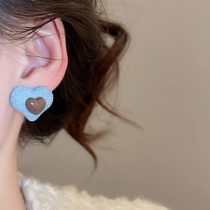 Close-up of blue fabric heart earrings with coffee brown glossy center on model