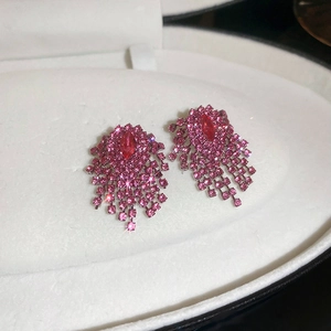 Macro detail of luxury pink gradient heart bow earrings with sparkling rhinestone tassels