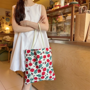 Détail du sac fourre-tout en toile à fleurs de rose porté par un mannequin en robe