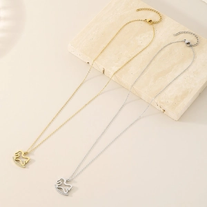 Detail of gold and silver rocking horse necklaces with sparkling crystals on a stone slab