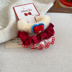 Close-up of plush polka dot scrunchies and heart bear hair ties on a warm linen background
