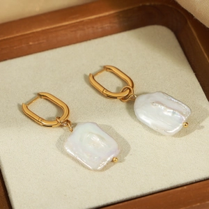 Vintage gold plated titanium earrings with irregular baroque pearls shown on a display tray