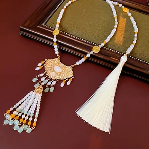 Detail of Chinese style pearl necklace with white jade pendant and silk tassel