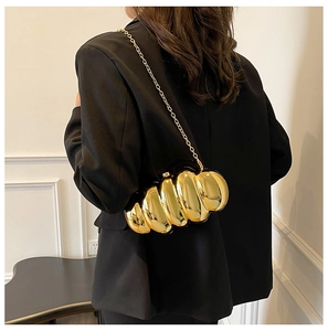 Chic gold metallic evening bag with spiral texture shown on a black blazer outfit