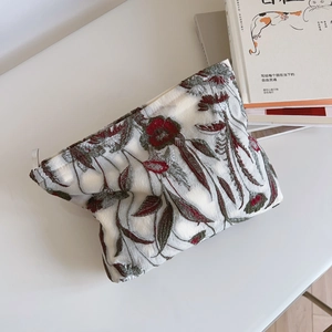 Macro detail of red floral embroidery on off-white vintage linen makeup bag fabric