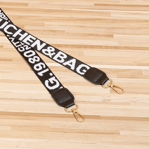 Detail of wide black canvas strap with gold metal swivel hooks and leather connectors