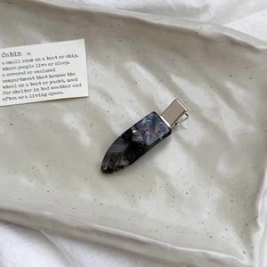 Detail of luxury teardrop hair clip with colorful rhinestones on marble acrylic