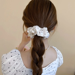 Close-up of a white and black polka dot scrunchie styled on a woman's high ponytail