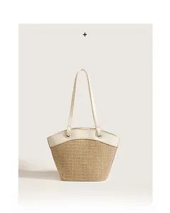 Detail of a fan-shaped woven straw bag with white leather handles and metal rings