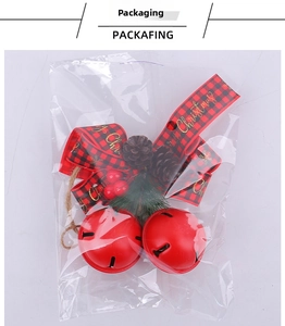 Christmas iron bells with red berries and bow in transparent plastic packaging