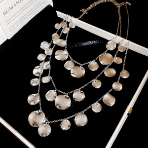 Close-up of triple-layered metal necklace with hammered round discs on black velvet