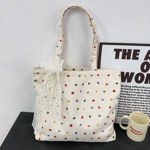 Detailed macro view of beige canvas tote bag with colorful polka dots and white lace bow